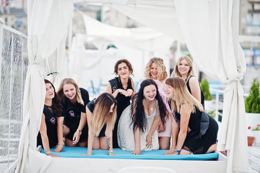 Group of 8 girls wear on black and 2 brides at hen party having fun at pier on beach side. photo