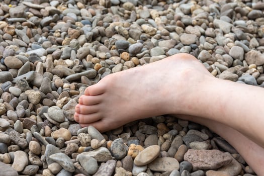 Partial view of a human bare foot on pebbles photo