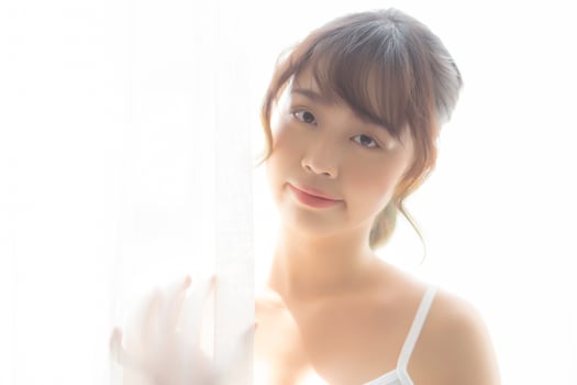 Portrait of beautiful young asian woman standing the window and smile while wake up with sunrise at morning, girl happy with freshness and cheerful, lifestyle and relax concept. photo