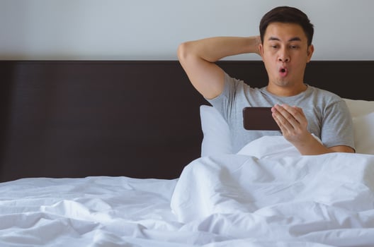 Asian man watching surprise news online at smart phone photo
