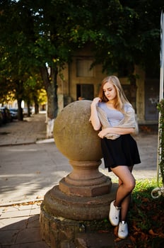Young blonde girl in black skirt with scarf posed at street of city. photo