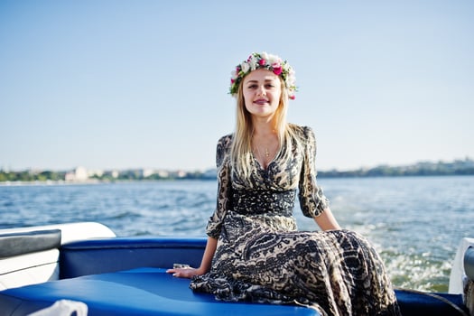 Blonde girl in wreath sitting on yacht at hen party. photo