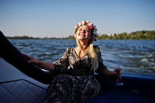 Blonde girl in wreath sitting on yacht at hen party with champagne. photo