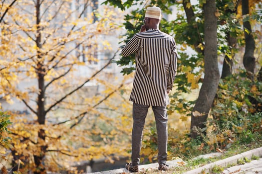 Back portrait of stylish black african american man at hat against autumn fall background. photo
