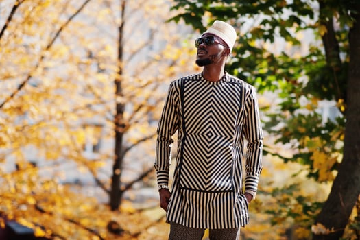 Portrait of stylish black african american man at hat and sunglasses against sunny autumn fall background. photo