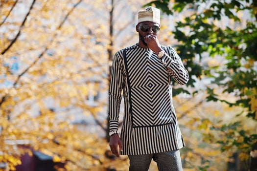 Portrait of stylish black african american man at hat and sunglasses against sunny autumn fall background. photo