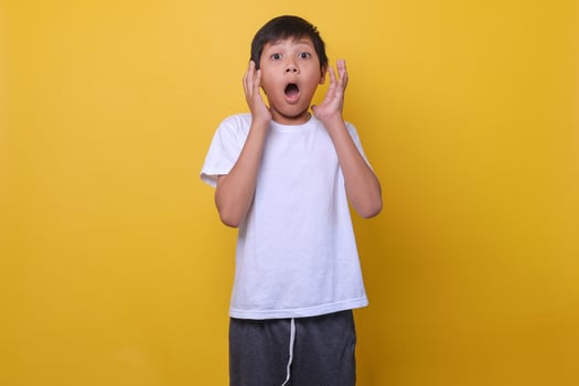 Asian boy in a casual style feeling suprised on yellow background. Mock up for kids fashion. photo