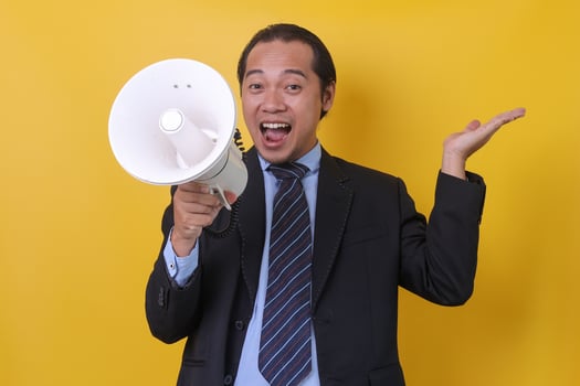 Asian businessman using megaphone during presentation, closeup portrait isolated on yellow background. photo