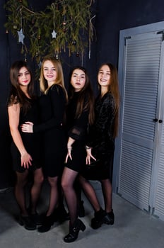 Four cute friends girls wear black dresses against christmas decoration. photo