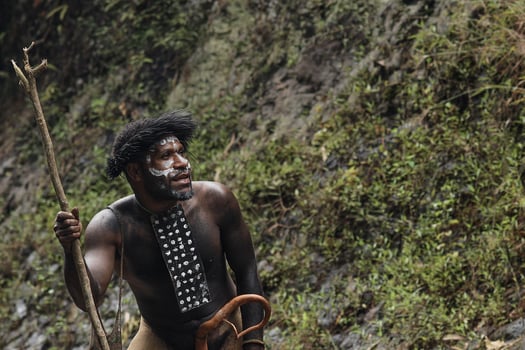 Dani Tribe man from Papua Indonesia wearing traditional costume and koteka is looking around to get the food. photo