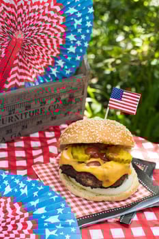 Fourth of July cheese burger with American flag on picnic table outdoors photo