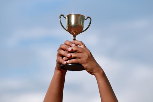 A winner success celebrating with trophy award and champion concept, Hand holding championship trophy against blue sky. photo