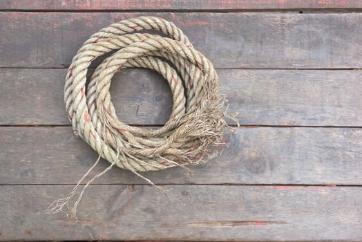 The rope rests on a wooden background photo