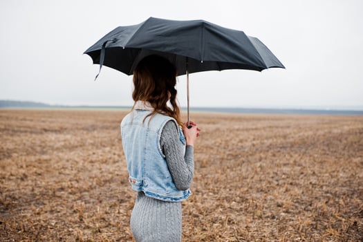 Portrait of brunette curly girl in jeans jacket with black umbrella at field. photo