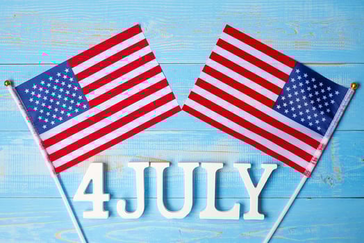 Fourth of July text and United States of America flag on wooden table background. USA holiday of Independence and celebration concepts photo