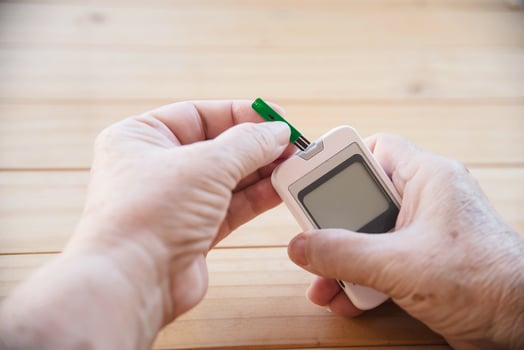 Old lady is testing blood sugar level using blood sugar test kid set - people with medical equipment concept photo