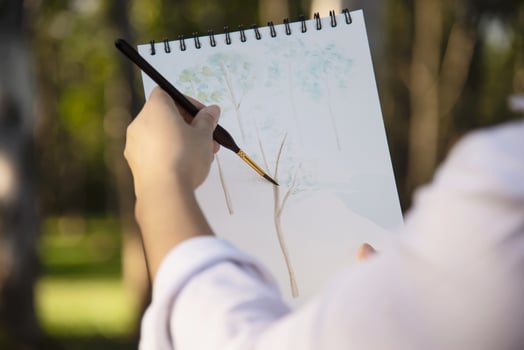 Relax woman painting water colour art work in green garden forest nature - people with creative art in nature stress reduction and meditation concept photo