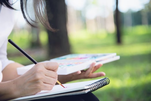 Relax woman painting water colour art work in green garden forest nature - people with creative art in nature stress reduction and meditation concept photo