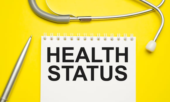 In the notebook is the text Health Status stethoscope, pills, and glasses photo