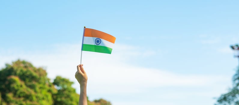 hand holding India flag on blue sky background. Holiday of India republic Day, happy Independence day and Gandhi Jayanti concepts photo