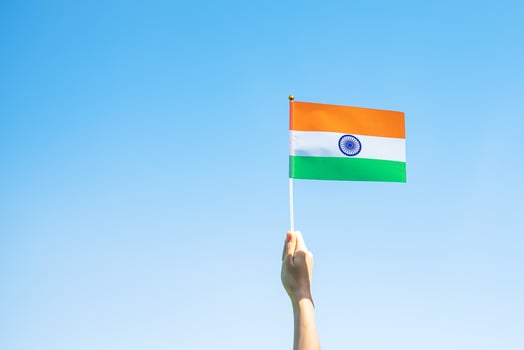hand holding India flag on blue sky background. Holiday of India republic Day, happy Independence day and Gandhi Jayanti concepts photo