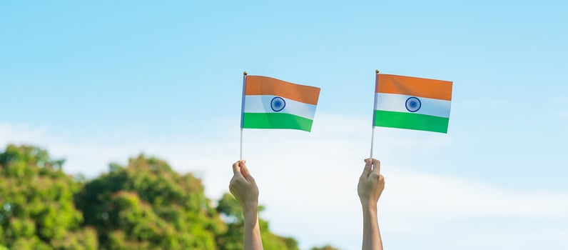 hand holding India flag on blue sky background. Holiday of India republic Day, happy Independence day and Gandhi Jayanti concepts photo
