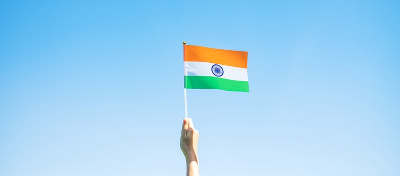 hand holding India flag on blue sky background. Holiday of India republic Day, happy Independence day and Gandhi Jayanti concepts photo