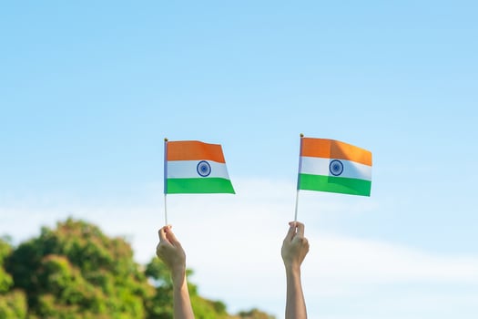 hand holding India flag on blue sky background. Holiday of India republic Day, happy Independence day and Gandhi Jayanti concepts photo