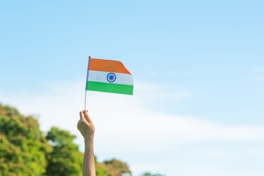 hand holding India flag on blue sky background. Holiday of India republic Day, happy Independence day and Gandhi Jayanti concepts photo