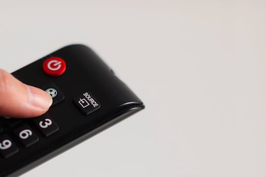 Thumb press the football button of television remote control. photo