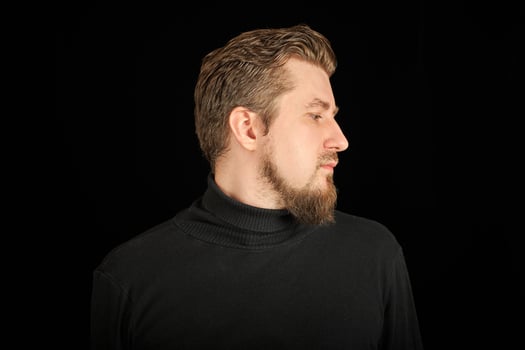 Cute bearded man, half-face portrait, black background photo