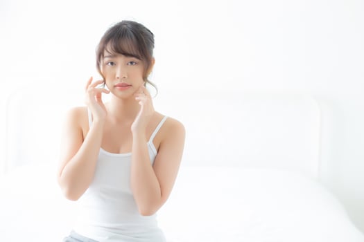 Portrait beautiful asian woman makeup of cosmetic, girl hand touch cheek and smile attractive, face beauty perfect with wellness in the bedroom at home with skin care and healthcare concept. photo