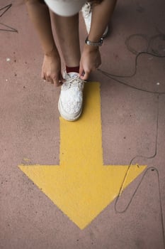 Feet and arrows on road. Yellow straight arrow sign and white shoes. Straight direction concept. Journey concept photo