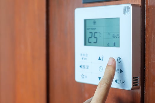 hand using remote controller for adjust Air conditioner inside the room of hotel or home photo