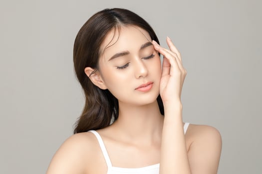 Beautiful young Asian woman model touch her face with perfect clean fresh skin on grey background. Face care, Facial treatment, Cosmetology, Plastic Surgery, Lovely girl portrait in studio. photo