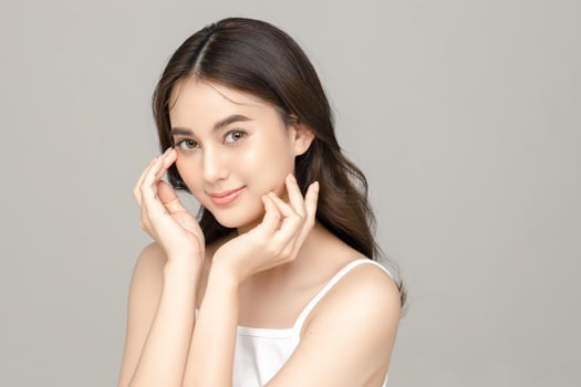 Beautiful young Asian woman model with perfect clean fresh skin on grey background. Face care, Facial treatment, Cosmetology, Plastic Surgery, Lovely girl portrait in studio. photo