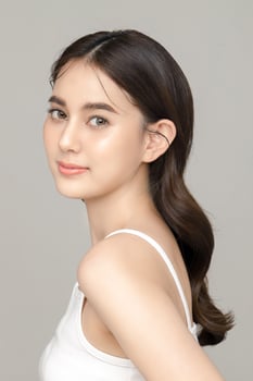 Beautiful young Asian woman model with perfect clean fresh skin on grey background. Face care, Facial treatment, Cosmetology, Plastic Surgery, Lovely girl portrait in studio. photo
