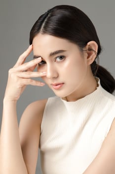 Beautiful young Asian woman model touch her face with perfect clean fresh skin on grey background. Face care, Facial treatment, Cosmetology, Plastic Surgery, Lovely girl portrait in studio. photo