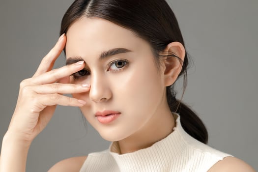 Beautiful young Asian woman model touch her face with perfect clean fresh skin on grey background. Face care, Facial treatment, Cosmetology, Plastic Surgery, Lovely girl portrait in studio. photo