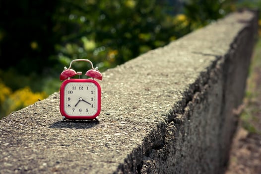 Red vintage style analog alarm clock on a concrete surface. photo