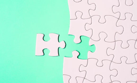 White jigsaw puzzle with some missing pieces on green background. Flat lay. photo