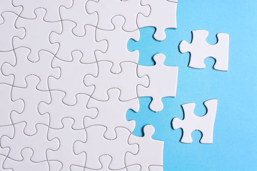 White jigsaw puzzle with some missing pieces on blue background. Copy space. photo