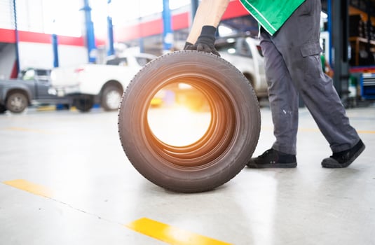 Technician holding a tire at a tire changing garage Set of four tires at a car service center photo