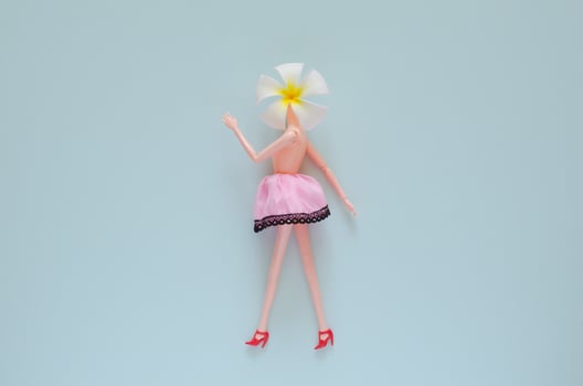 Female doll posing with Frangipani flower. Minimal beauty and fashion concept. photo