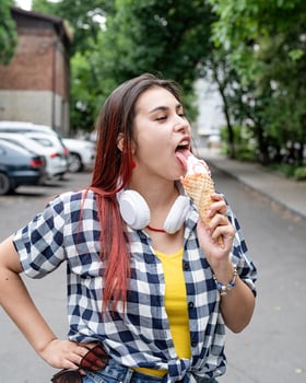 cheerful trendy woman with red hair eating ice cream at street in summer heat photo
