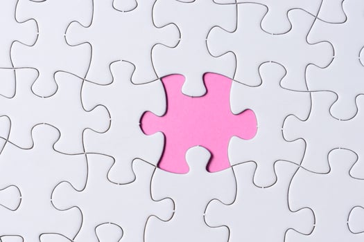 Piece of jigsaw puzzle on pink paper. Flat lay, Directly above. photo