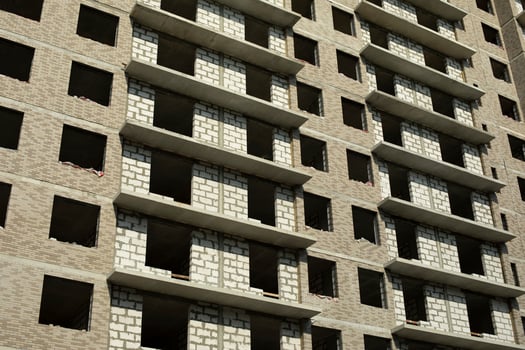 Empty windows in building. Unfinished house in city. Construction on street. photo