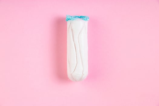 Hygienic cotton tampon on pink background. Feminine menstrual hygiene product. photo