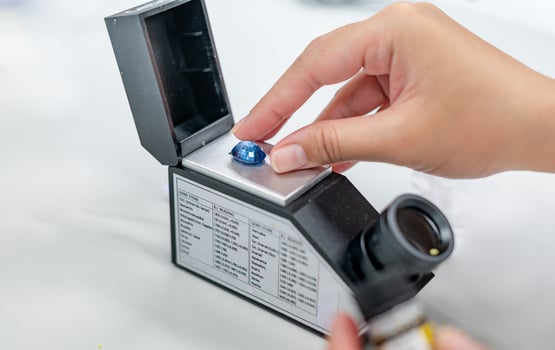 Female hand holding the blue precious stone and put on the refractometer for confirm the type of stone photo