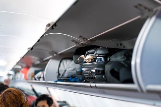 luggage on airplane shelf overhead passenger seat photo